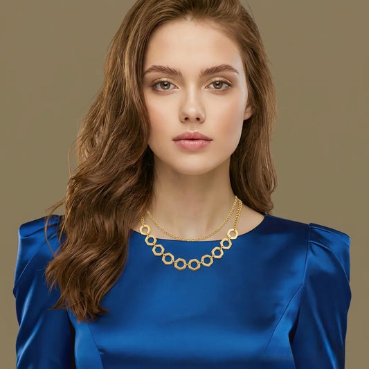 Woman wearing a blue dress and gold necklace against a beige background