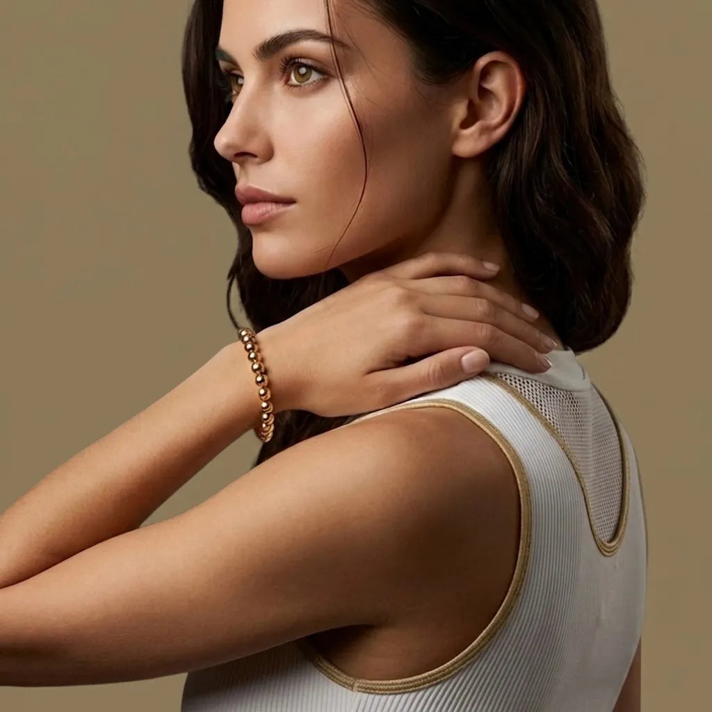 Woman wearing a white sleeveless top with gold trim against a beige background