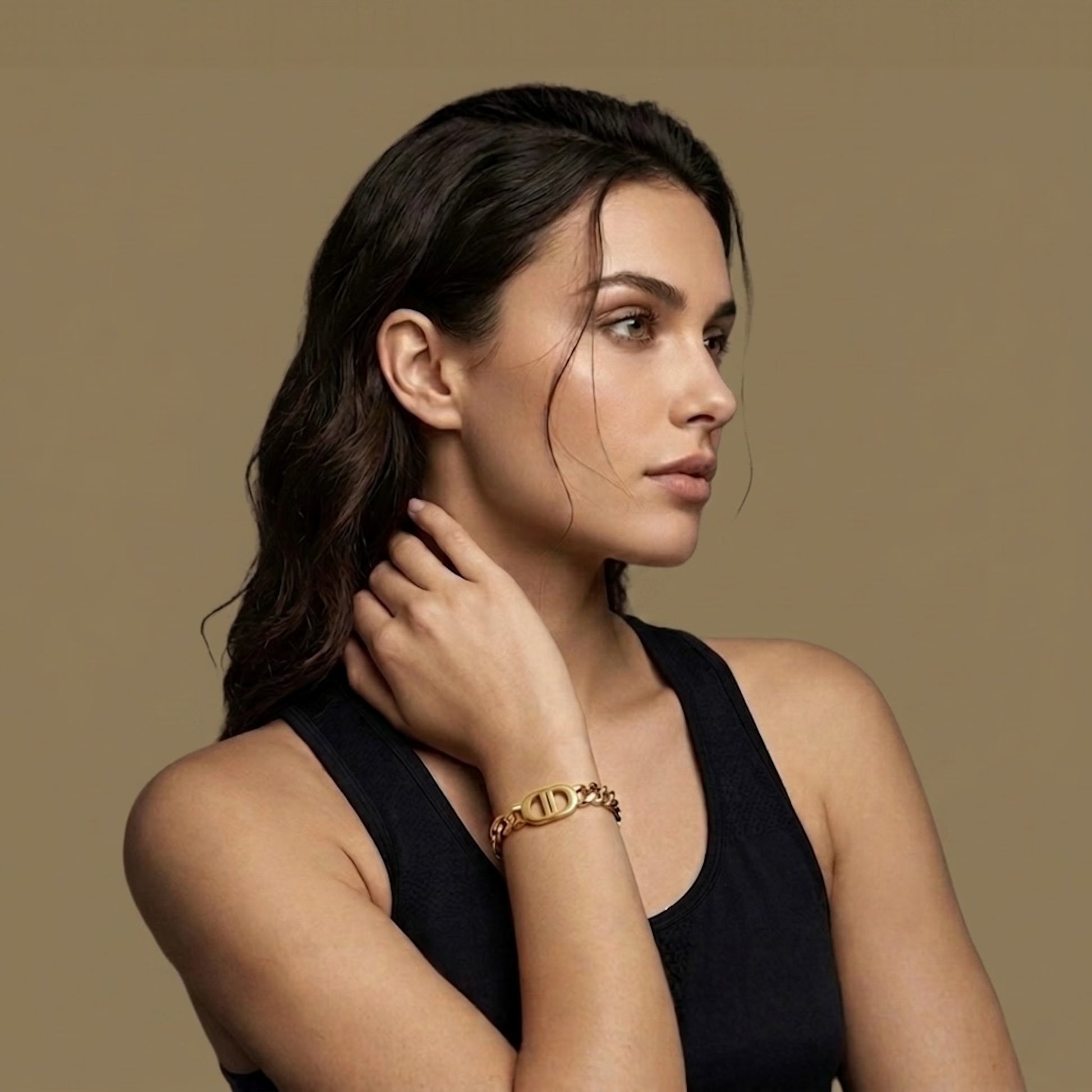 woman in black wearing a golden chain bracelet on a golden background
