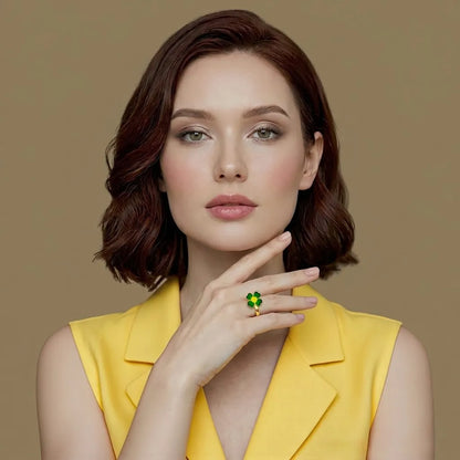 Woman wearing a yellow sleeveless top with a green ring on her finger against a brown background