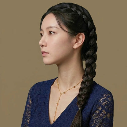 Woman with braided hair wearing a blue lace top against a brown background
