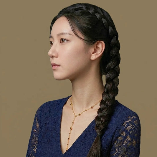 Woman with braided hair wearing a blue lace top against a brown background