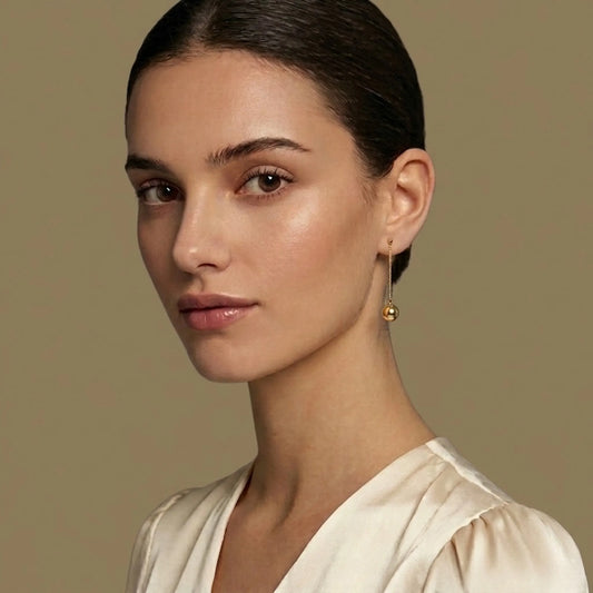 Woman wearing gold earrings against a beige background