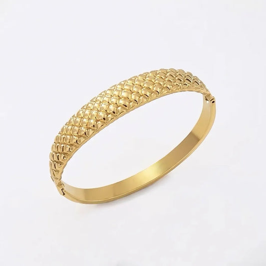 Gold bracelet with cushion textured pattern on a white background
