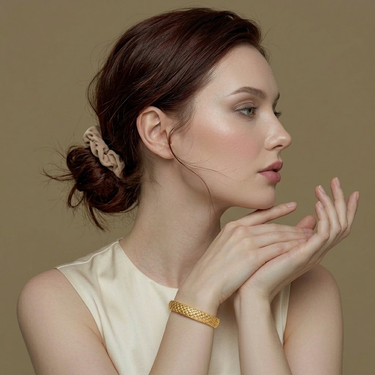 Woman with a cushion shaped gold bracelet on a golden background