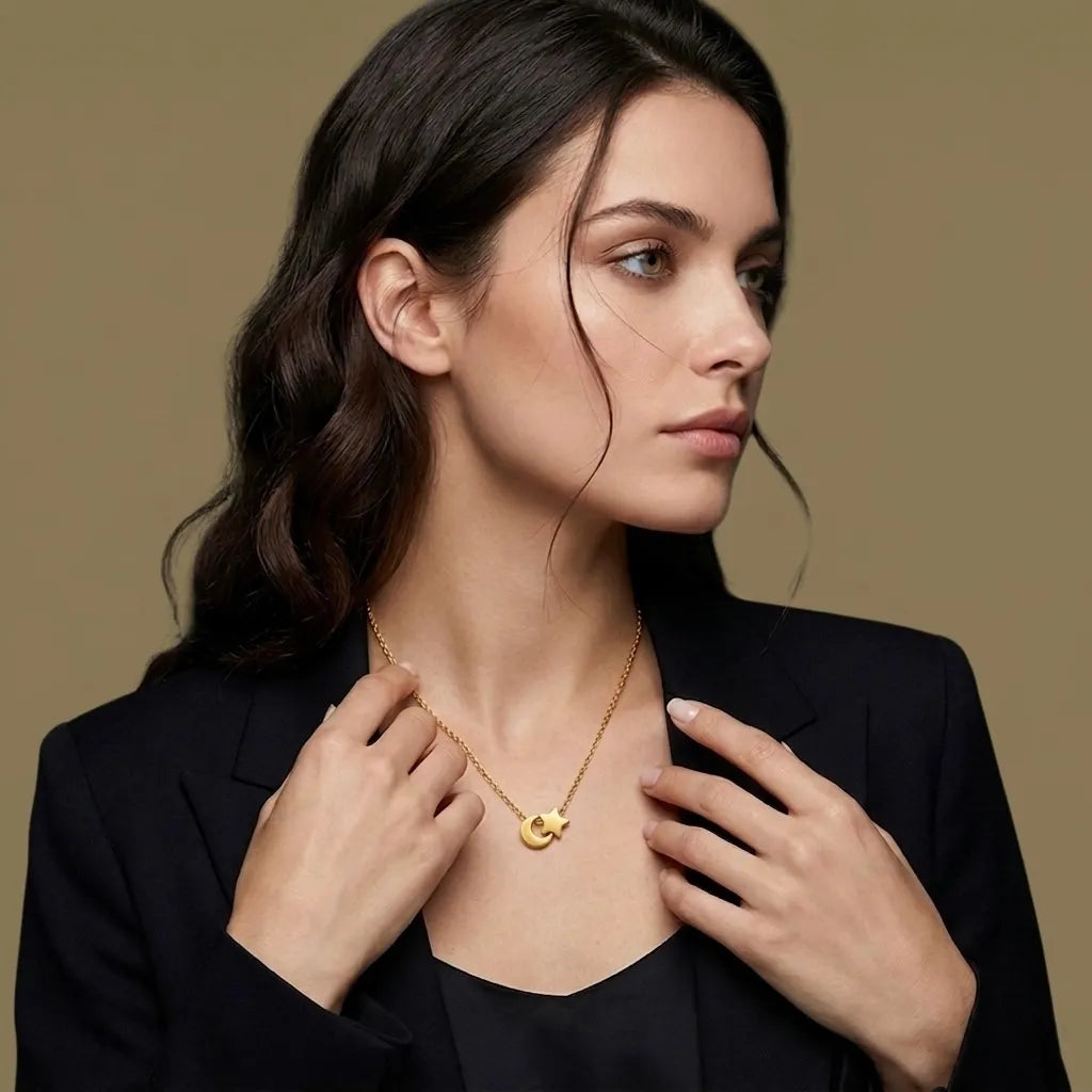 Woman wearing a gold necklace with a crescent moon pendant against a beige background