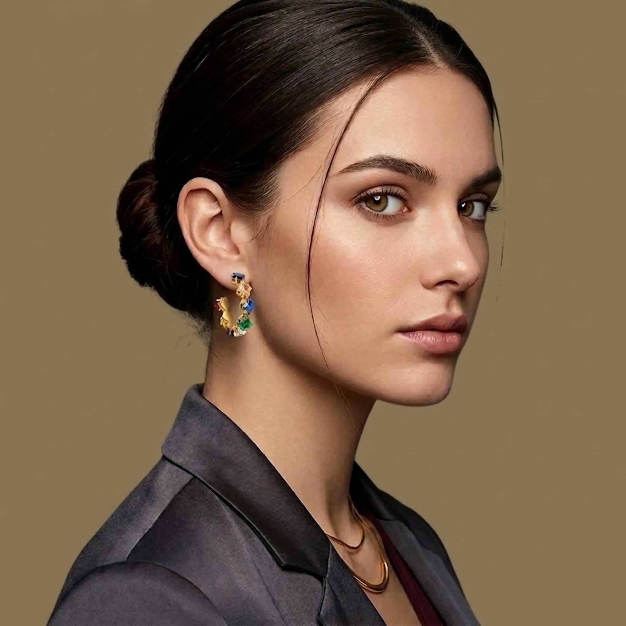 Woman wearing colorful earrings against a beige background