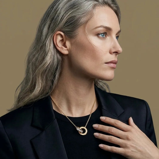 Woman wearing a gold necklace against a beige background