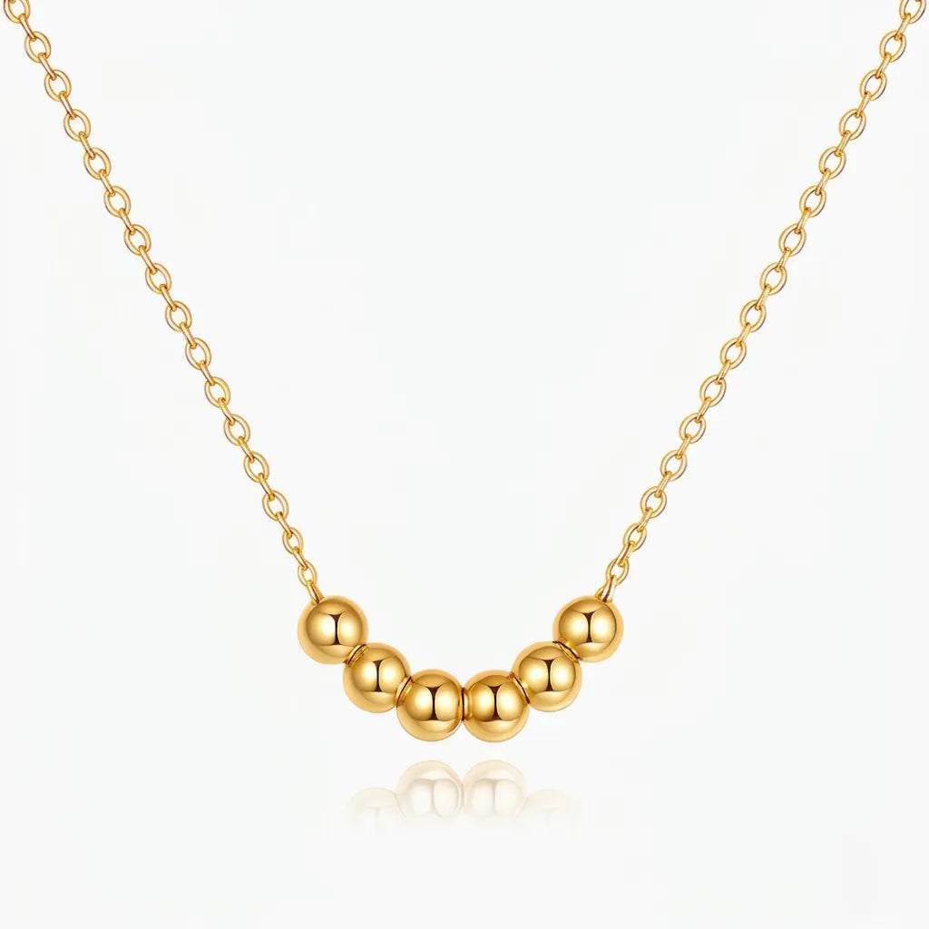 Gold necklace with round beads on a white background
