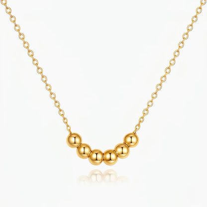 Gold necklace with round beads on a white background