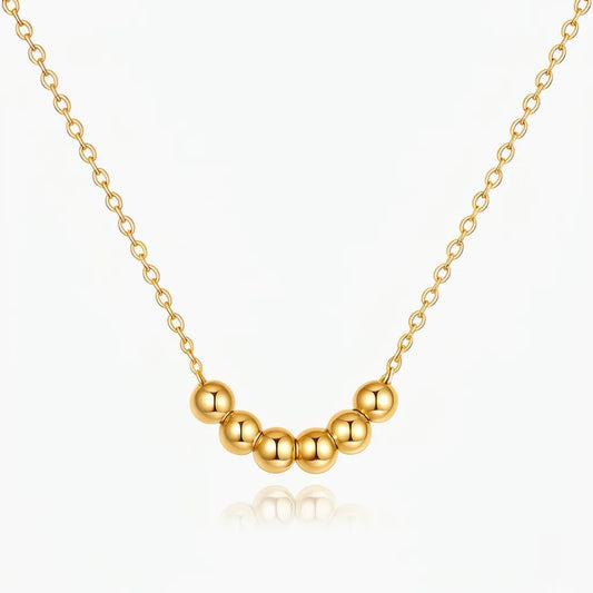 Gold necklace with round beads on a white background