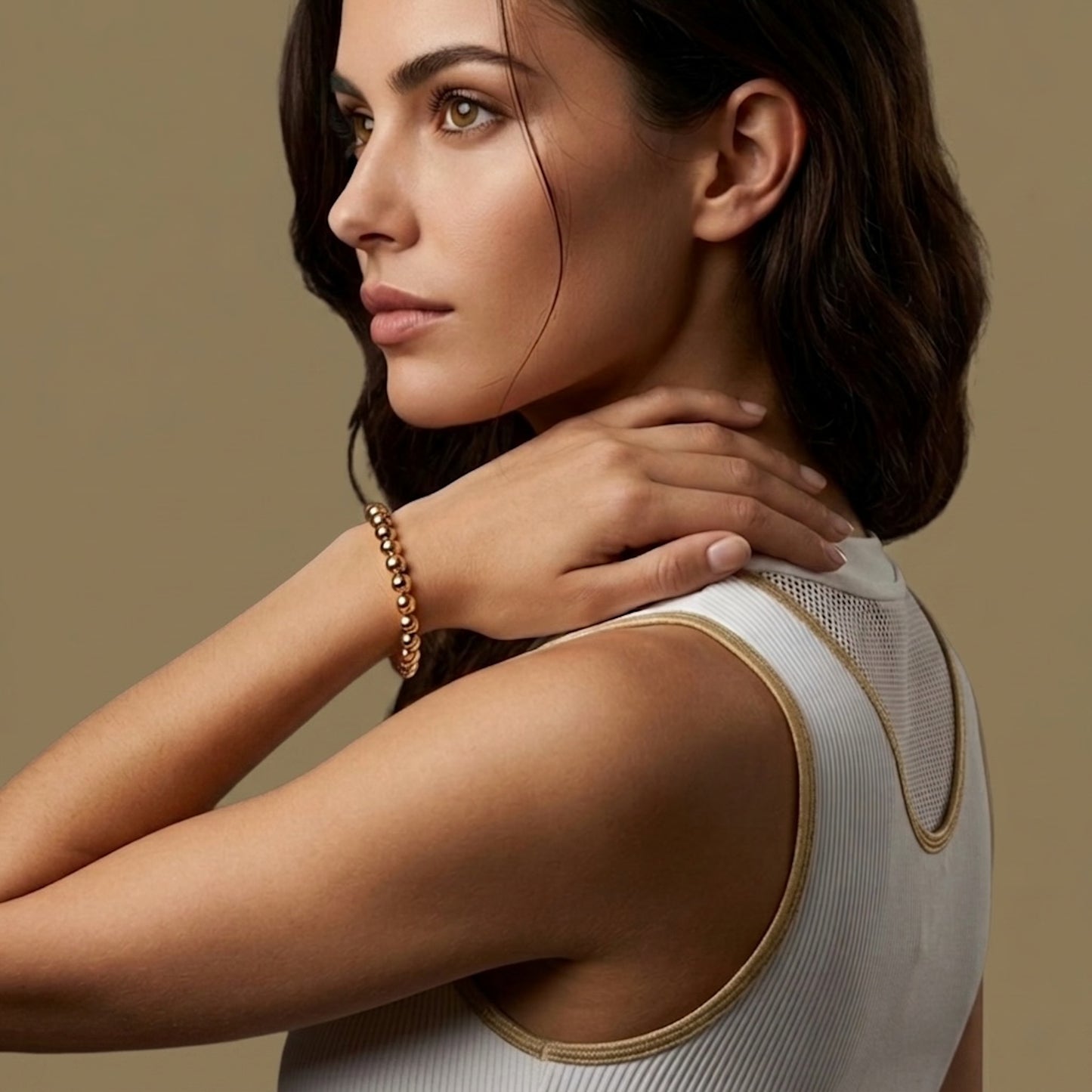 Woman wearing a golden tennis bracelet on a golden background