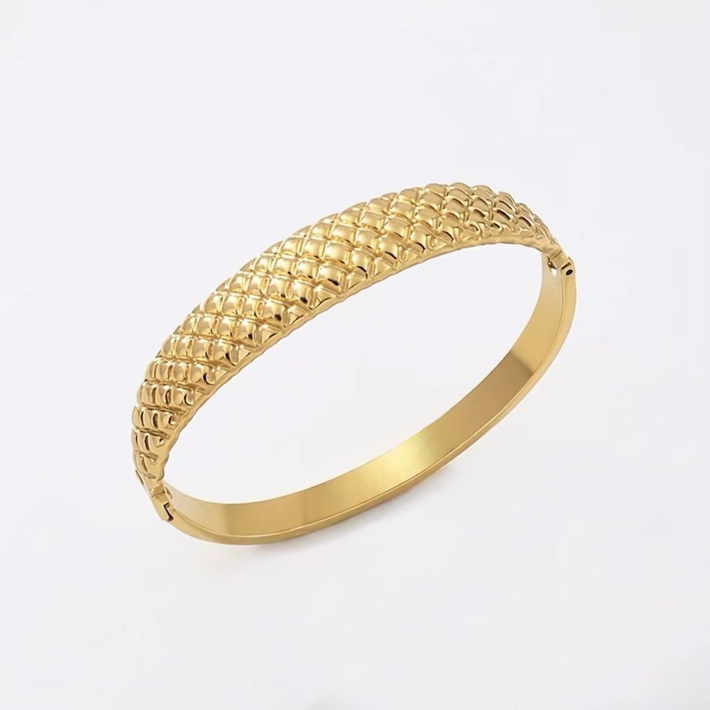 Gold bracelet with cushion textured design on a white background