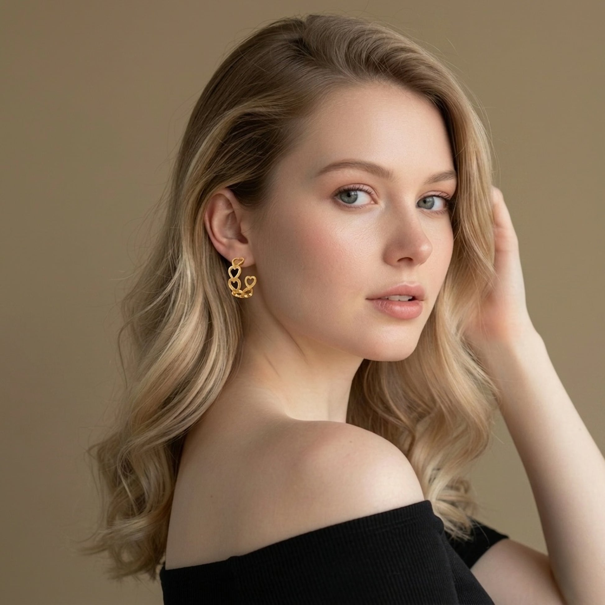 Woman wearing heart-shaped gold earrings on a golden background